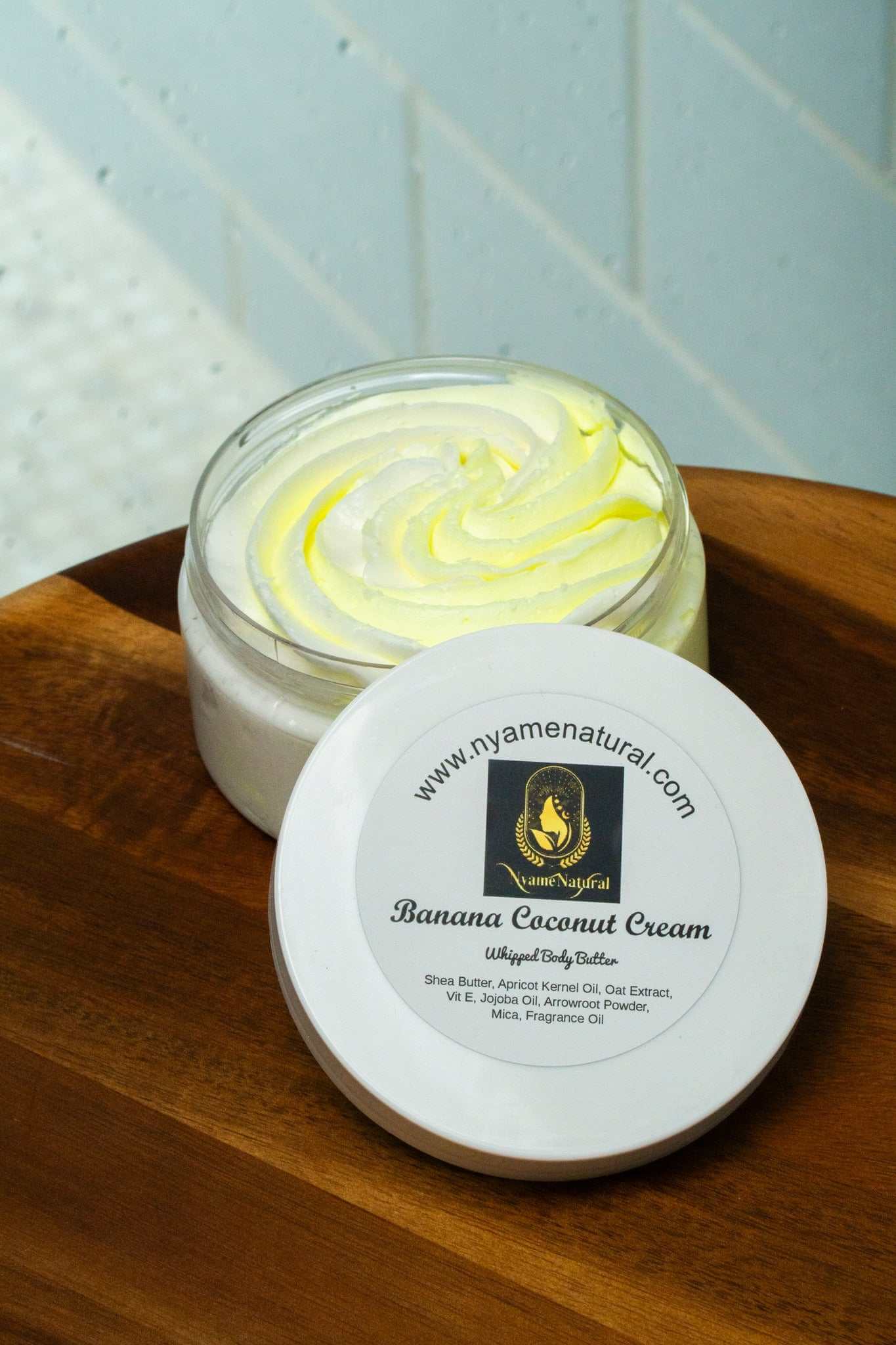 Banana Coconut Cream Body Butter in a jar with whipped texture on a wooden surface, perfect for nourishment and hydration.