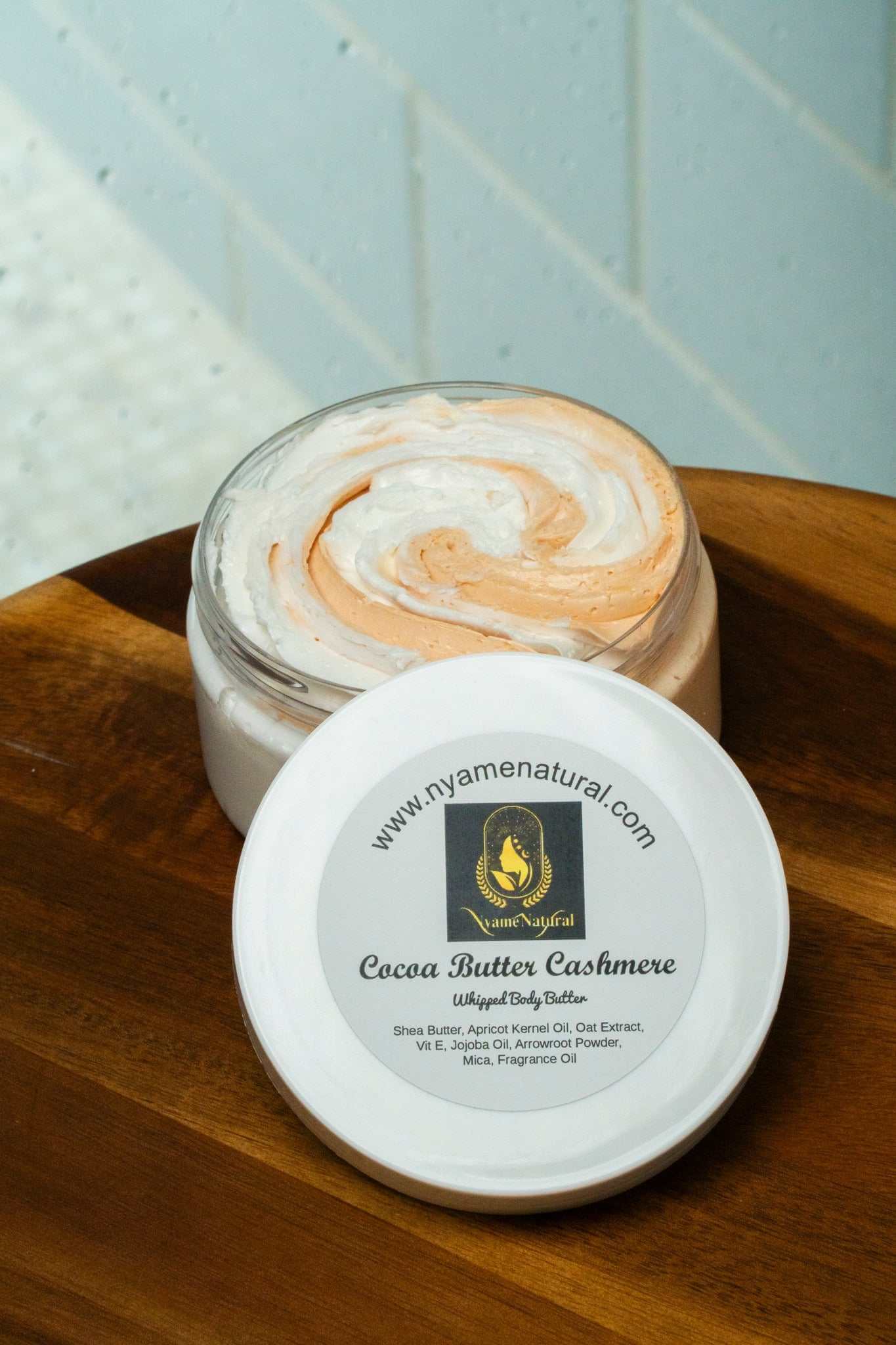 Cocoa Butter Cashmere body butter in a clear jar, showcasing a creamy swirl of soft orange and white texture.