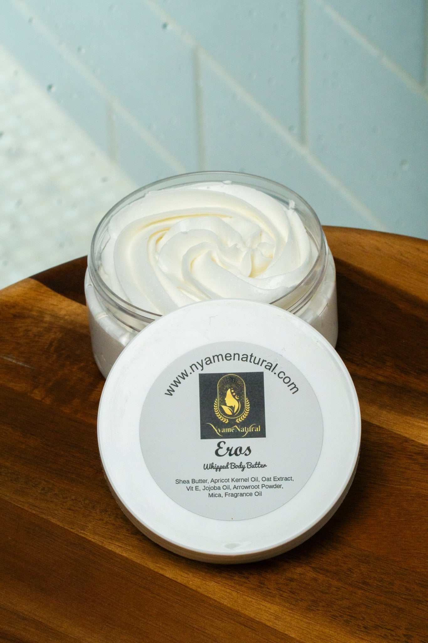 Eros Body Butter in a jar, showcasing a creamy texture on a wooden surface, highlighting its luxurious and nourishing formula.