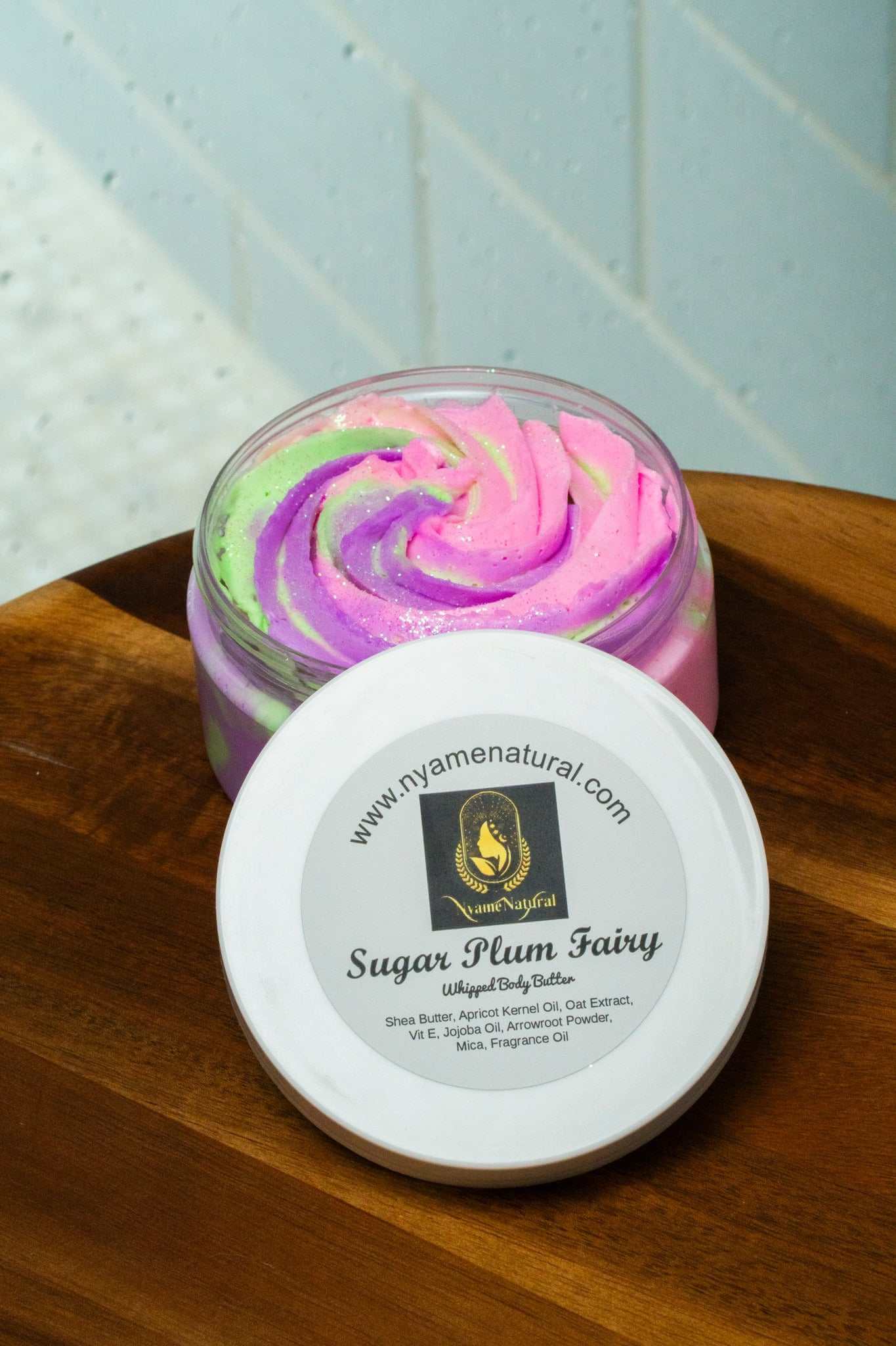 Sugar Plum Fairy Body Butter in a colorful jar, showcasing its silky texture and vibrant swirls.