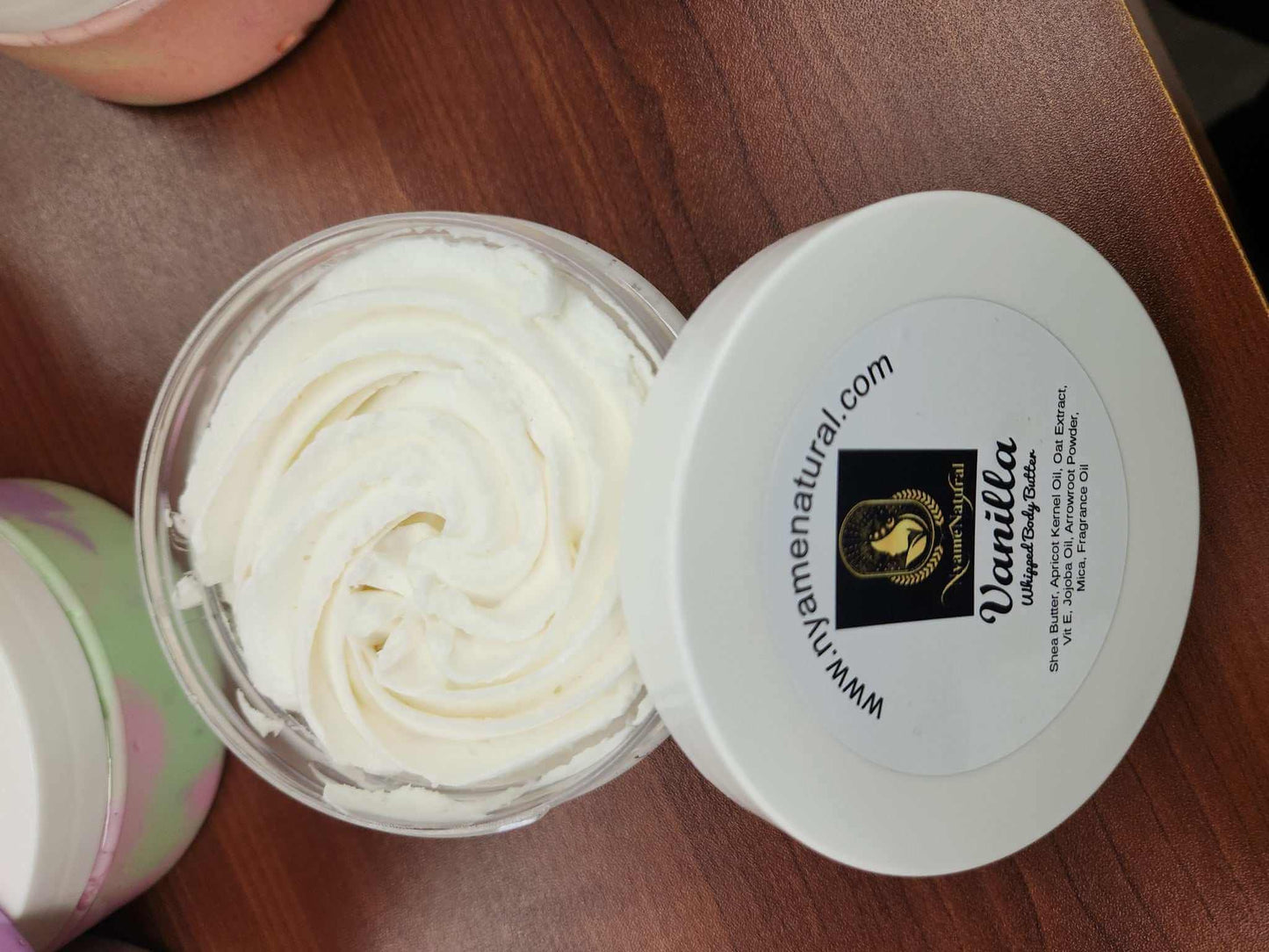 Luxurious Vanilla Body Butter in a clear jar with creamy texture on a wooden surface.