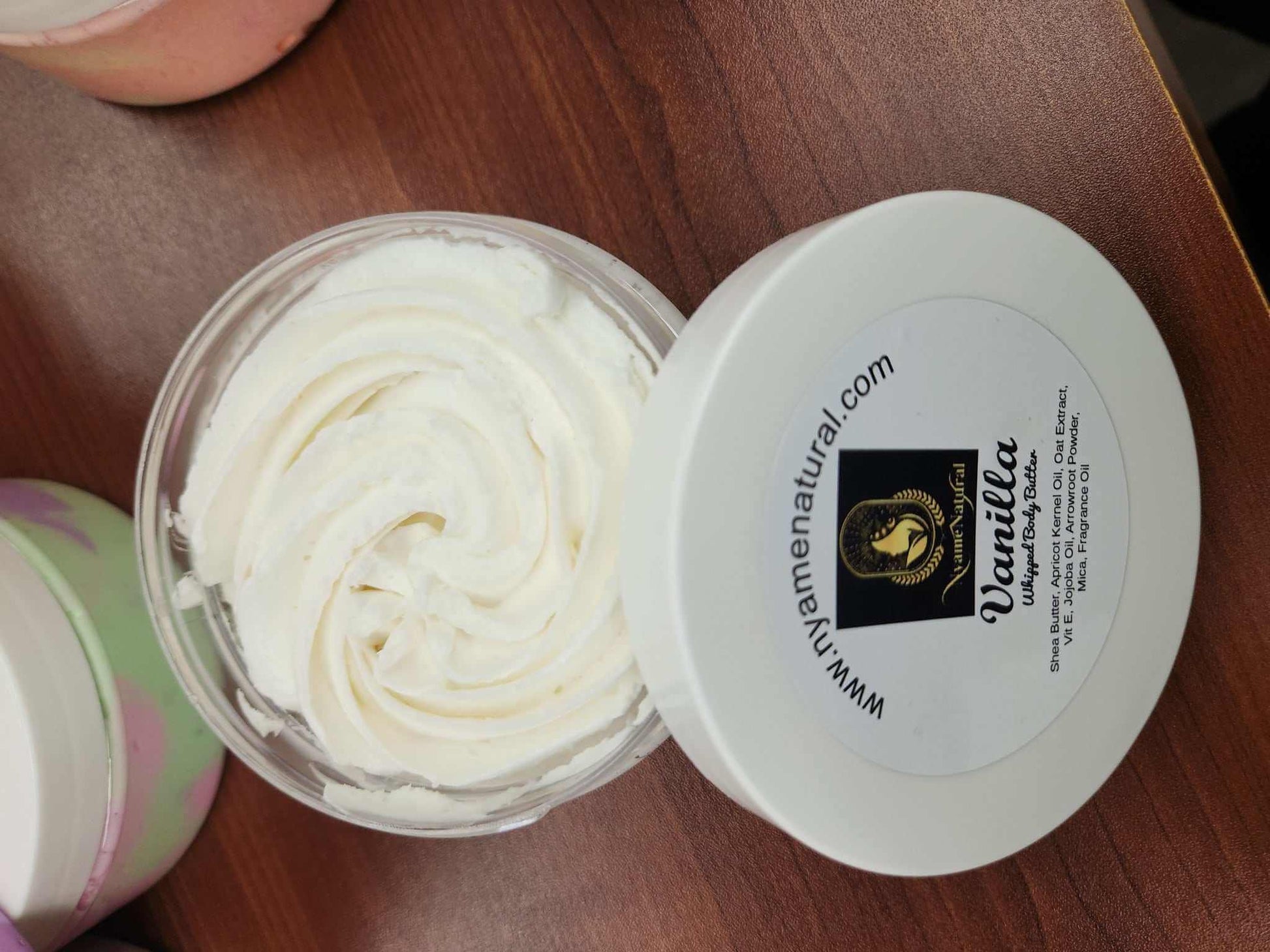 Luxurious Vanilla Body Butter in a clear jar with creamy texture on a wooden surface.