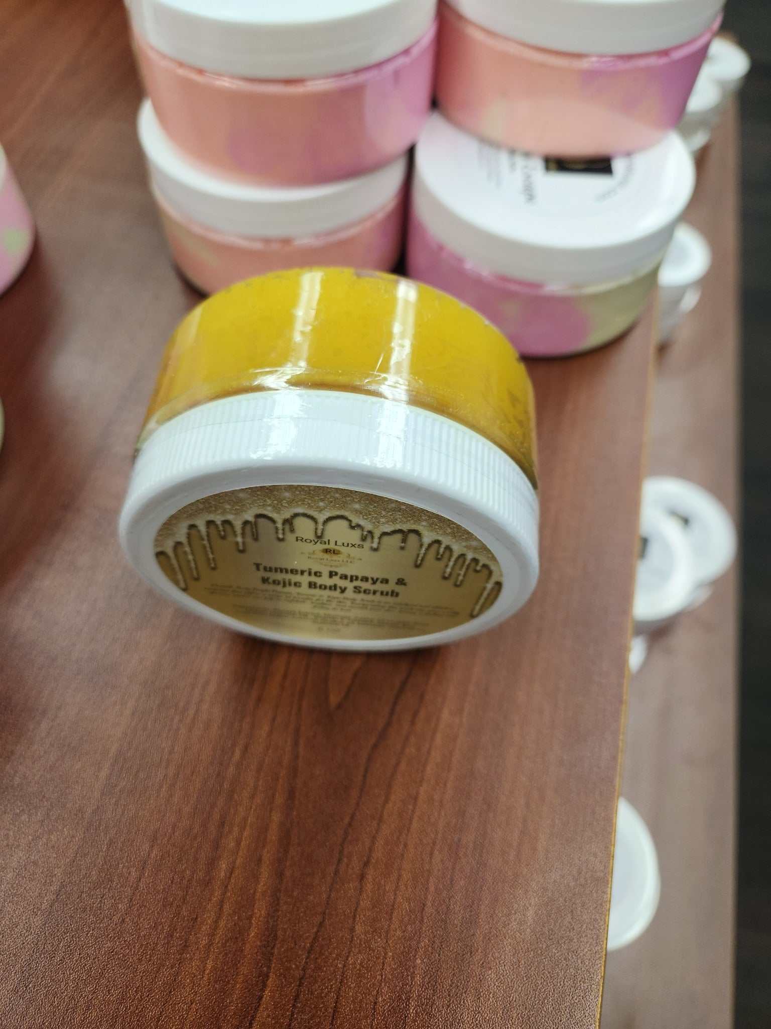 Bright Turmeric Papaya & Niacinamide Body Scrub in a yellow jar on a wooden display.
