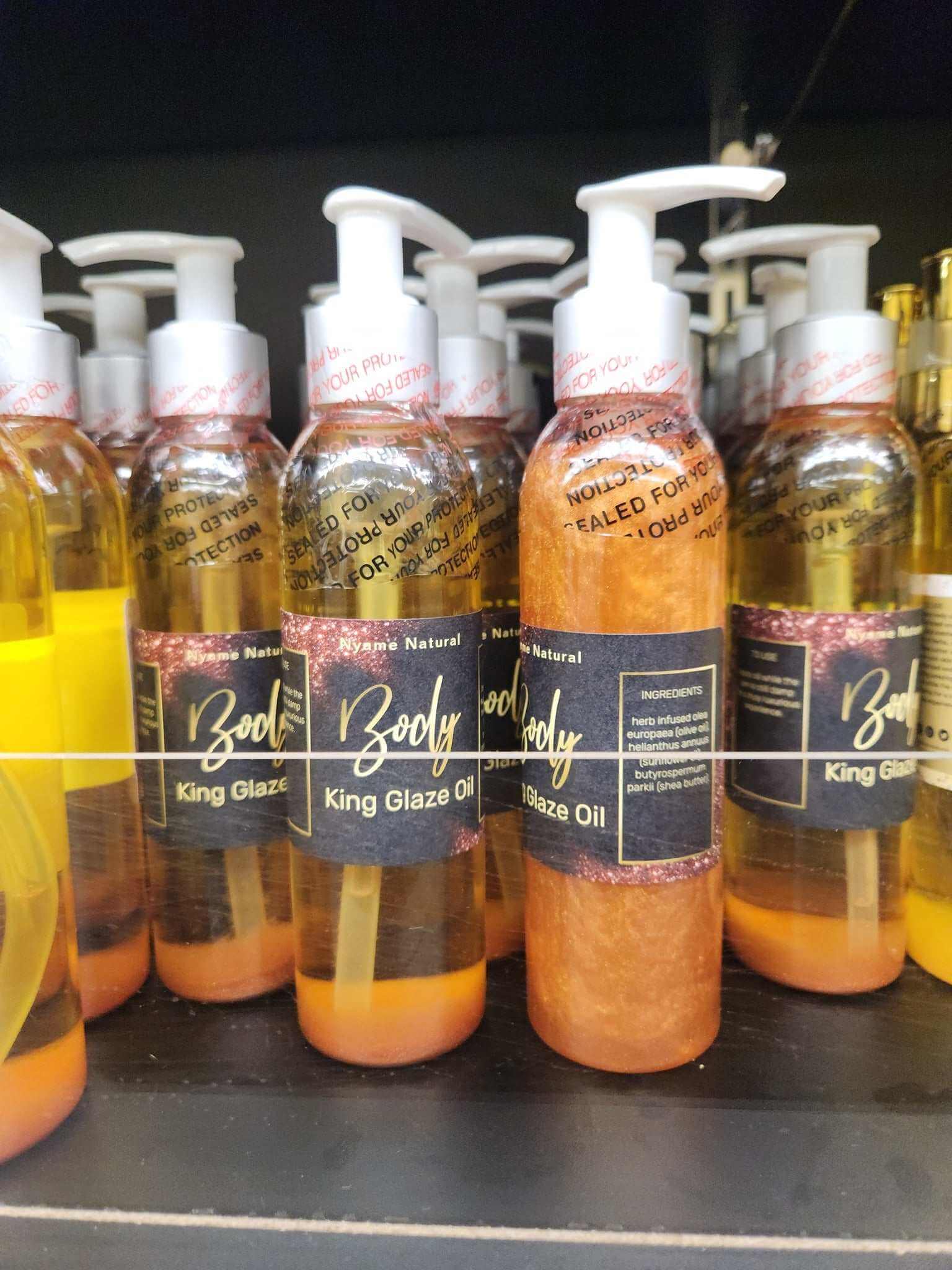 King Glaze Pheromone Oil bottles on a shelf, showcasing luxurious body oil with a shimmering finish.