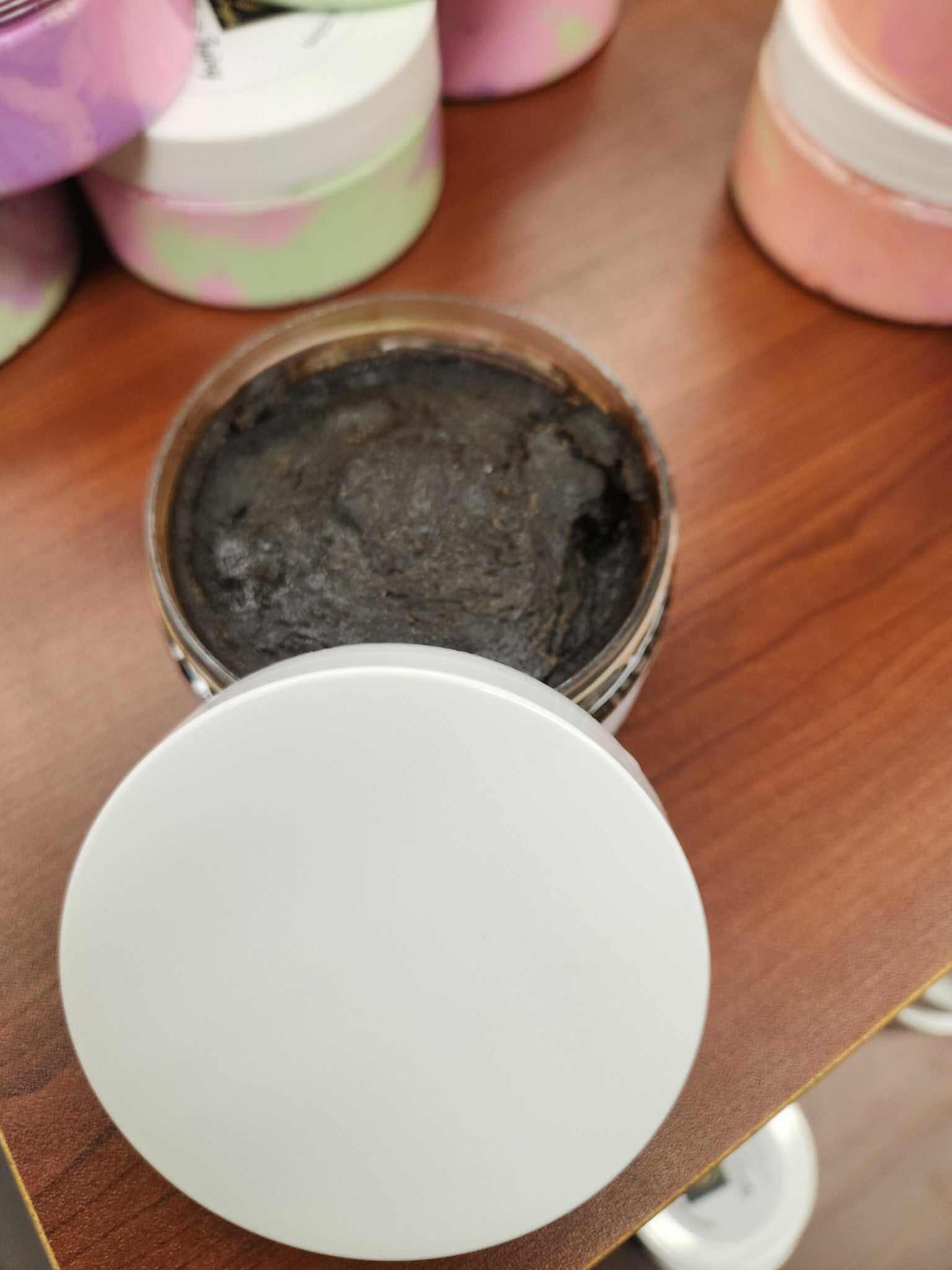 Open jar of Black Soap Paste showcasing its rich, dark texture on a wooden surface.