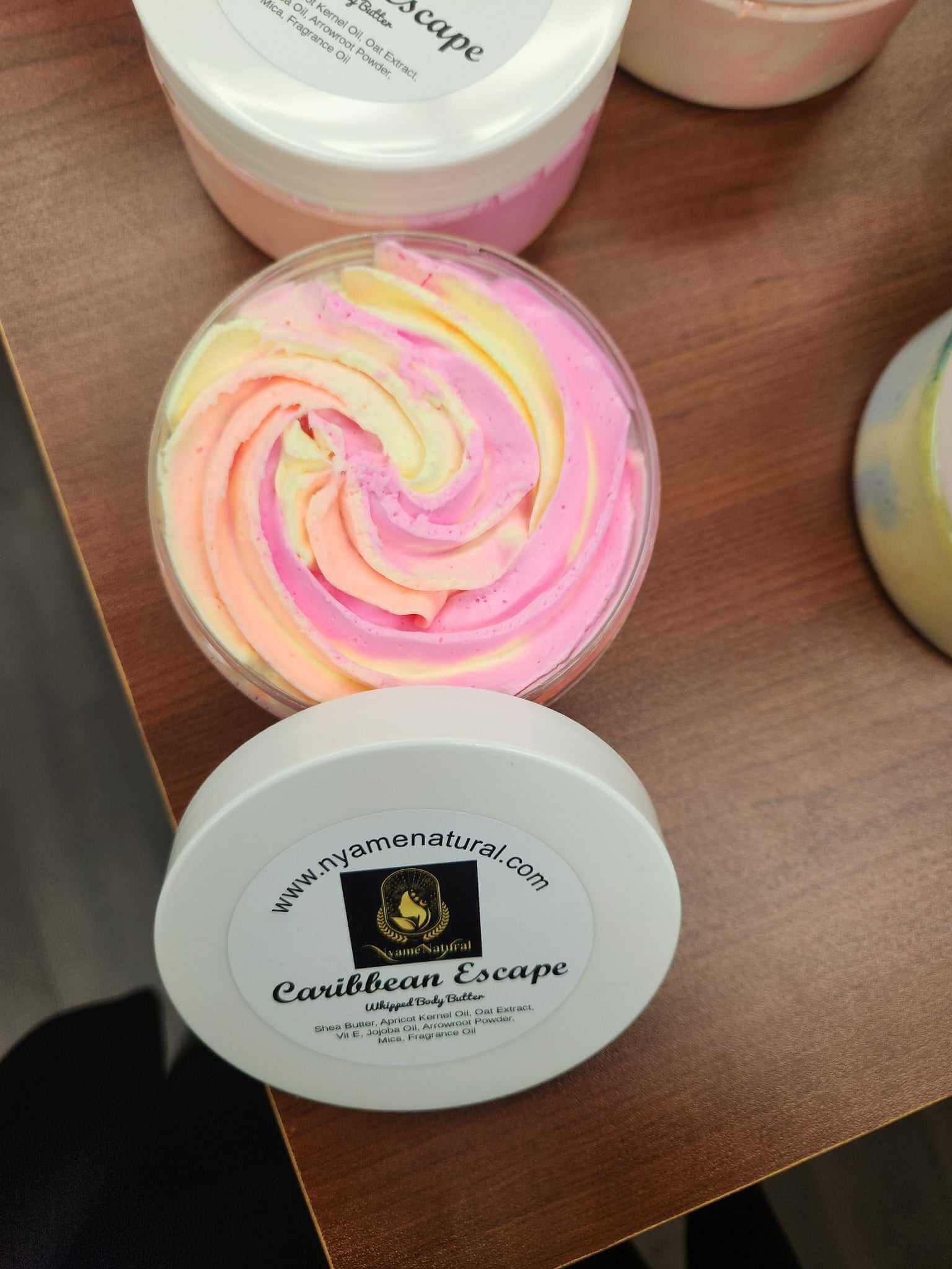 Colorful Caribbean Escape Body Butter in a jar with a creamy swirl on a wooden table.