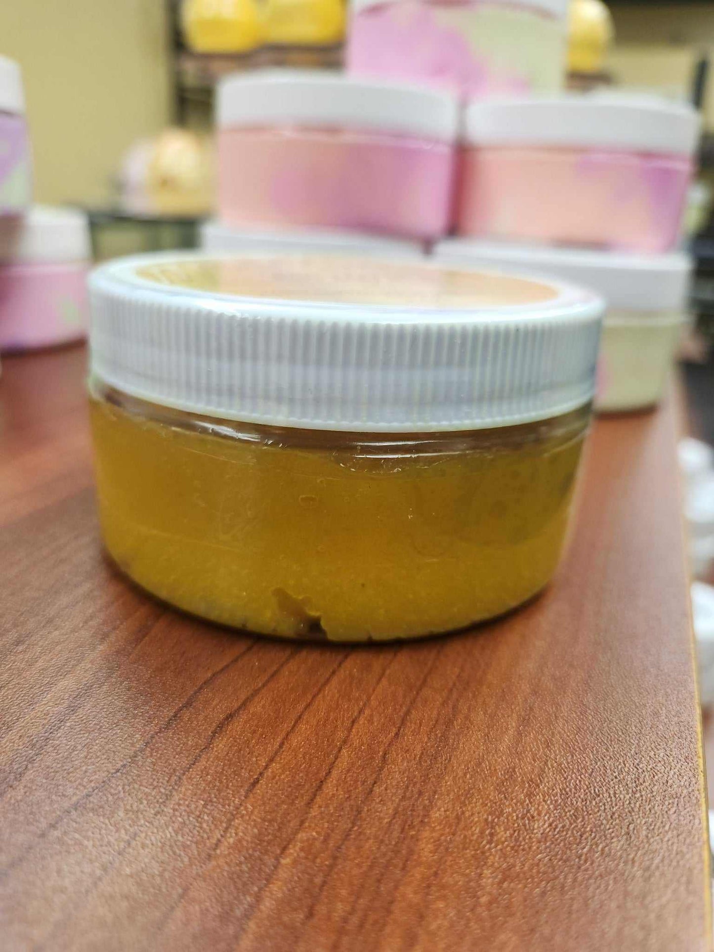Bright Turmeric Papaya & Niacinamide Body Scrub in a clear jar on a wooden surface.