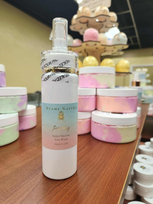Sweet Yoni Wash bottle on display with colorful jars in the background, promoting freshness and organic ingredients.