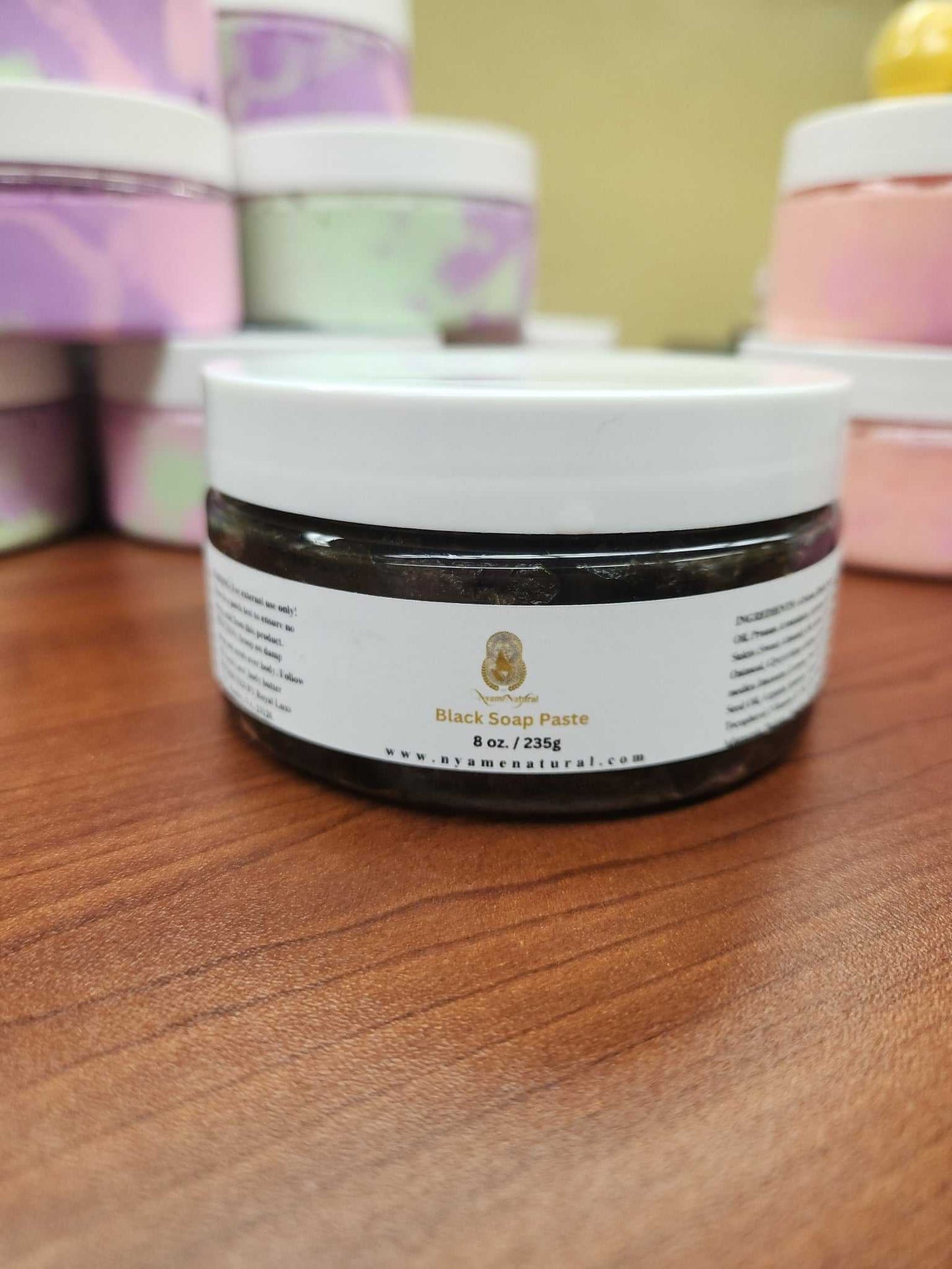 Black Soap Paste jar on wooden surface, ideal for acne reduction and dark spot healing.