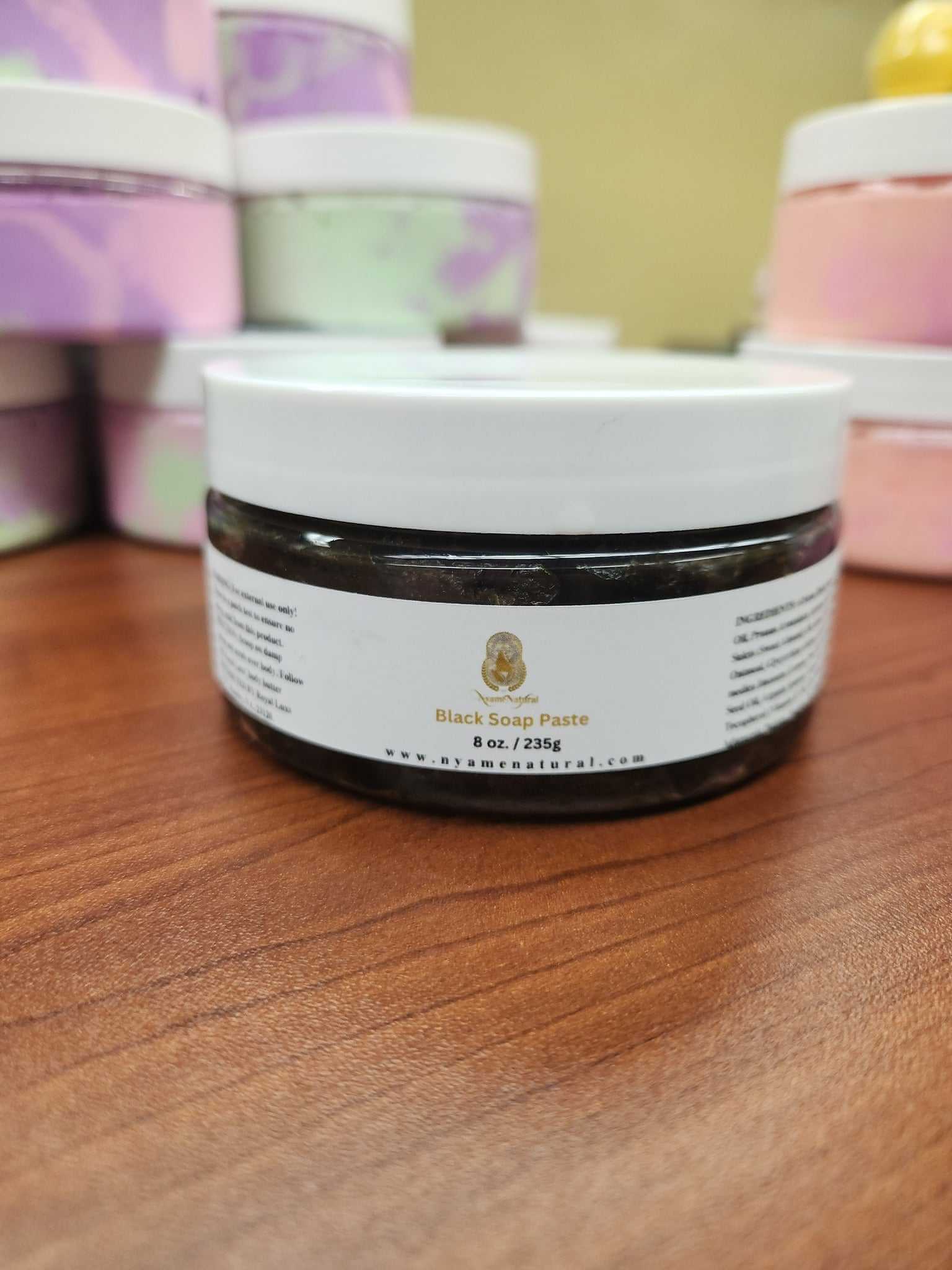 Black Soap Paste jar on wooden surface, ideal for acne reduction and dark spot healing.