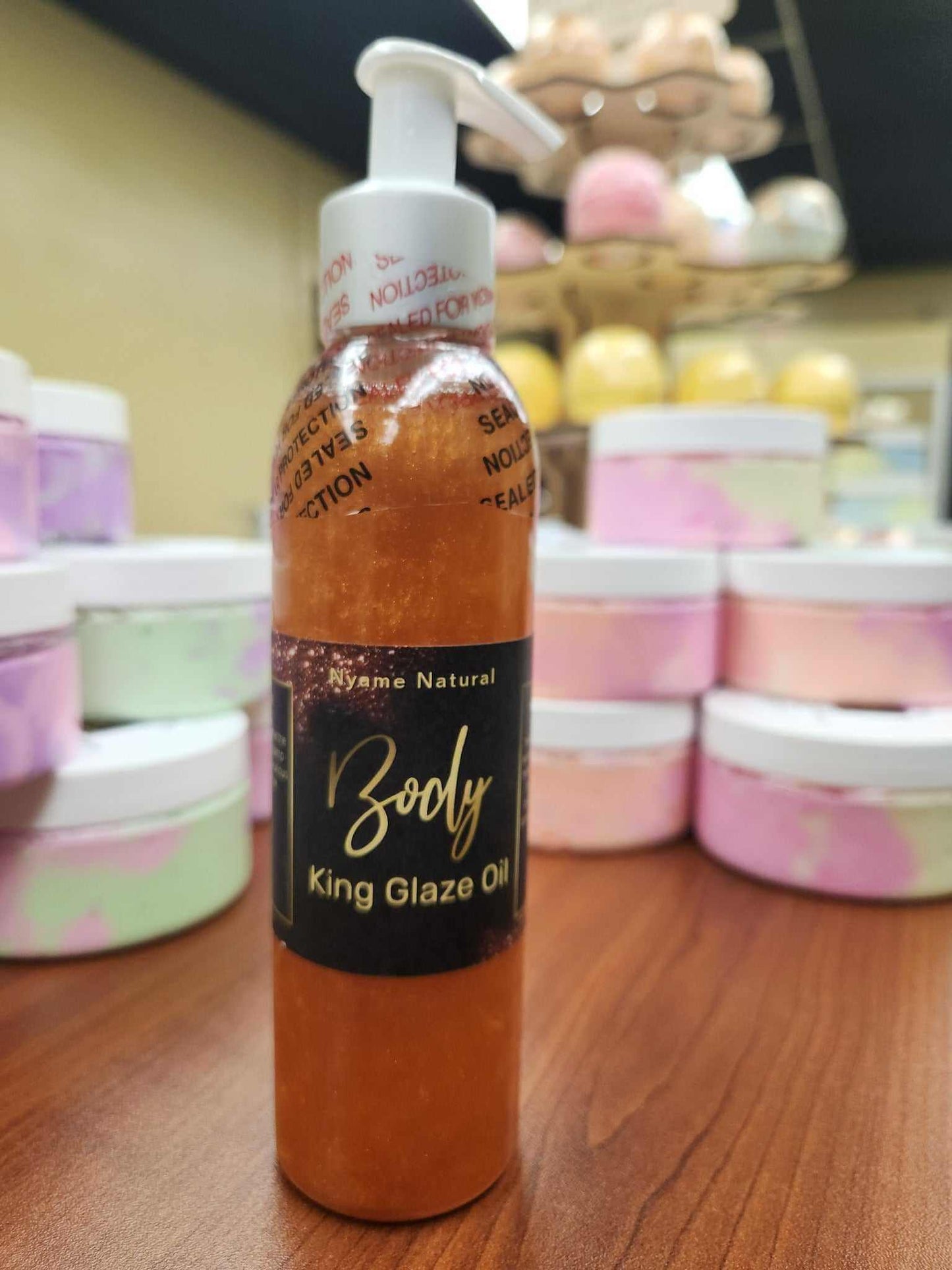 King Glaze Pheromone Oil bottle with golden sheen, displayed among colorful body creams.