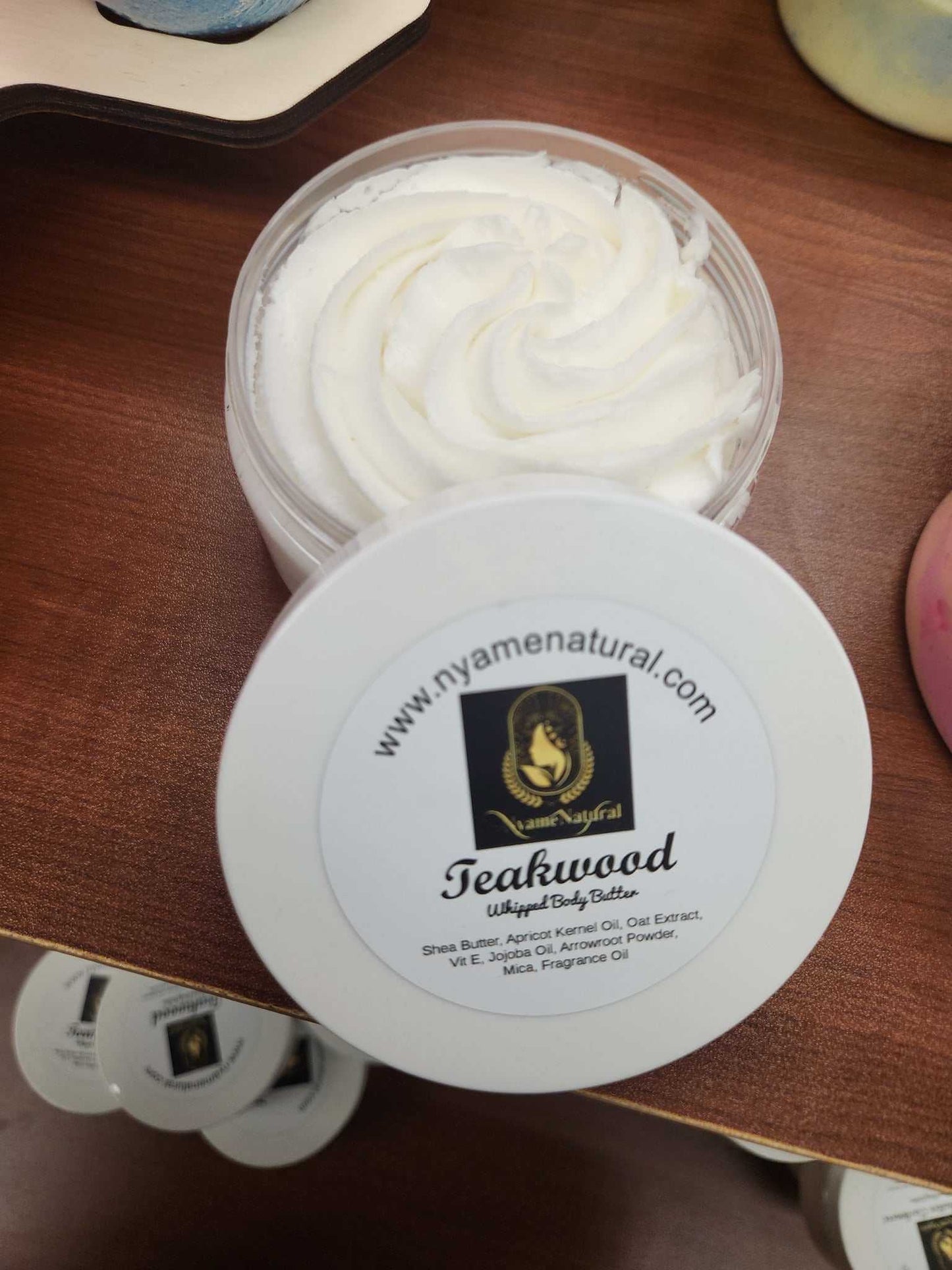 Teakwood Body Butter in a clear container with a white lid, showcasing its rich, creamy texture.