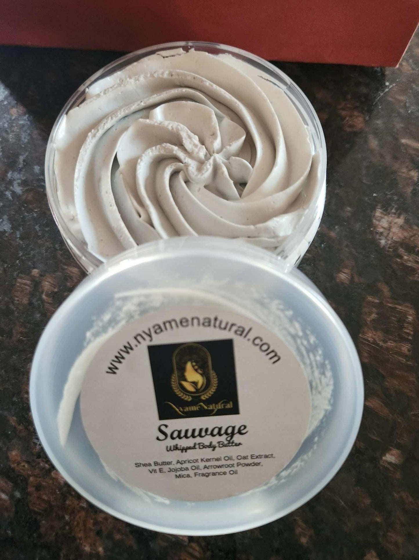 Sauvage Luxury Body Butter in a clear container with a silky whipped texture, showcasing its nourishing properties.