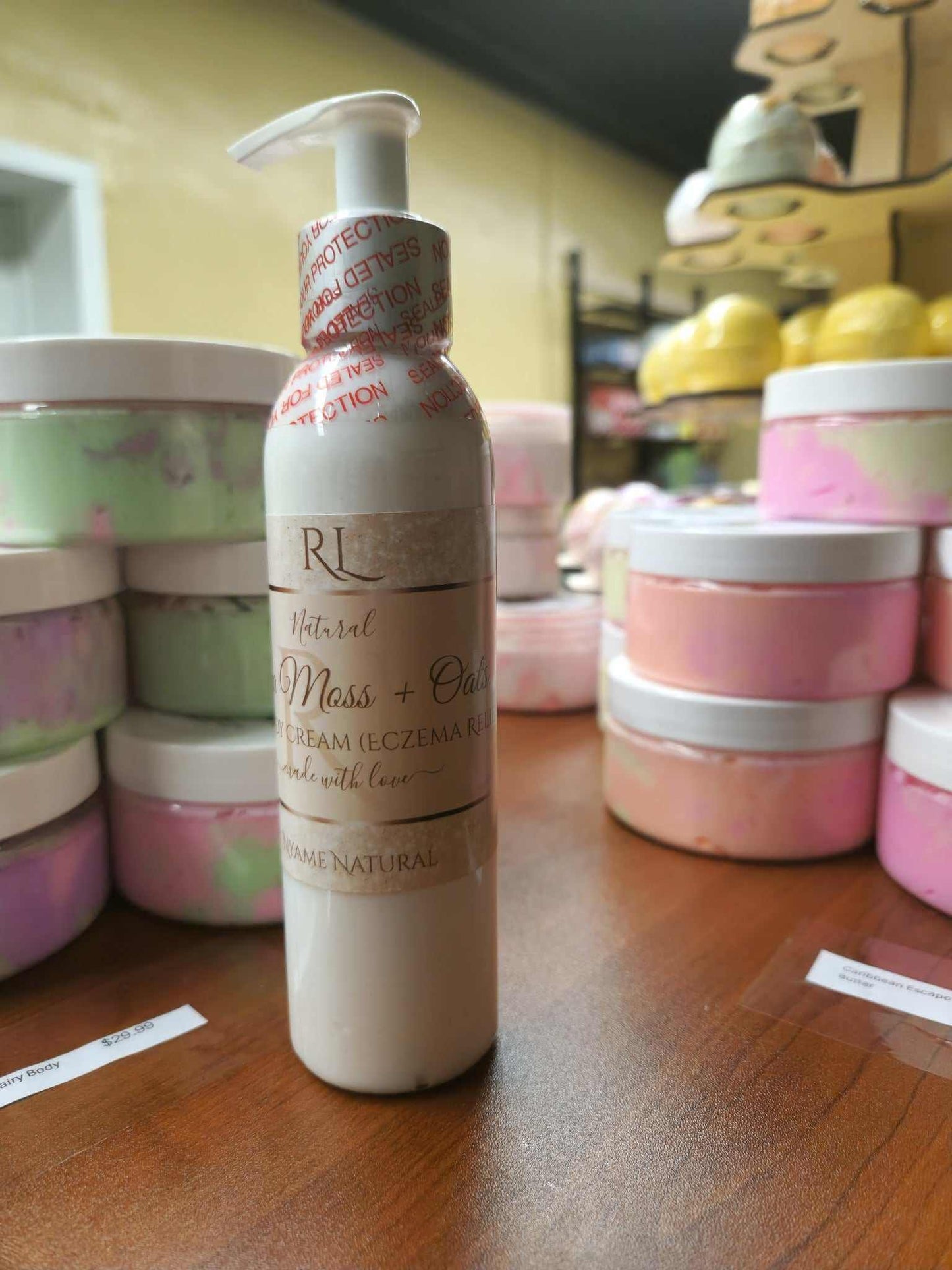 Sea Moss body cream for eczema next to colorful jars of skincare products on a wooden table.