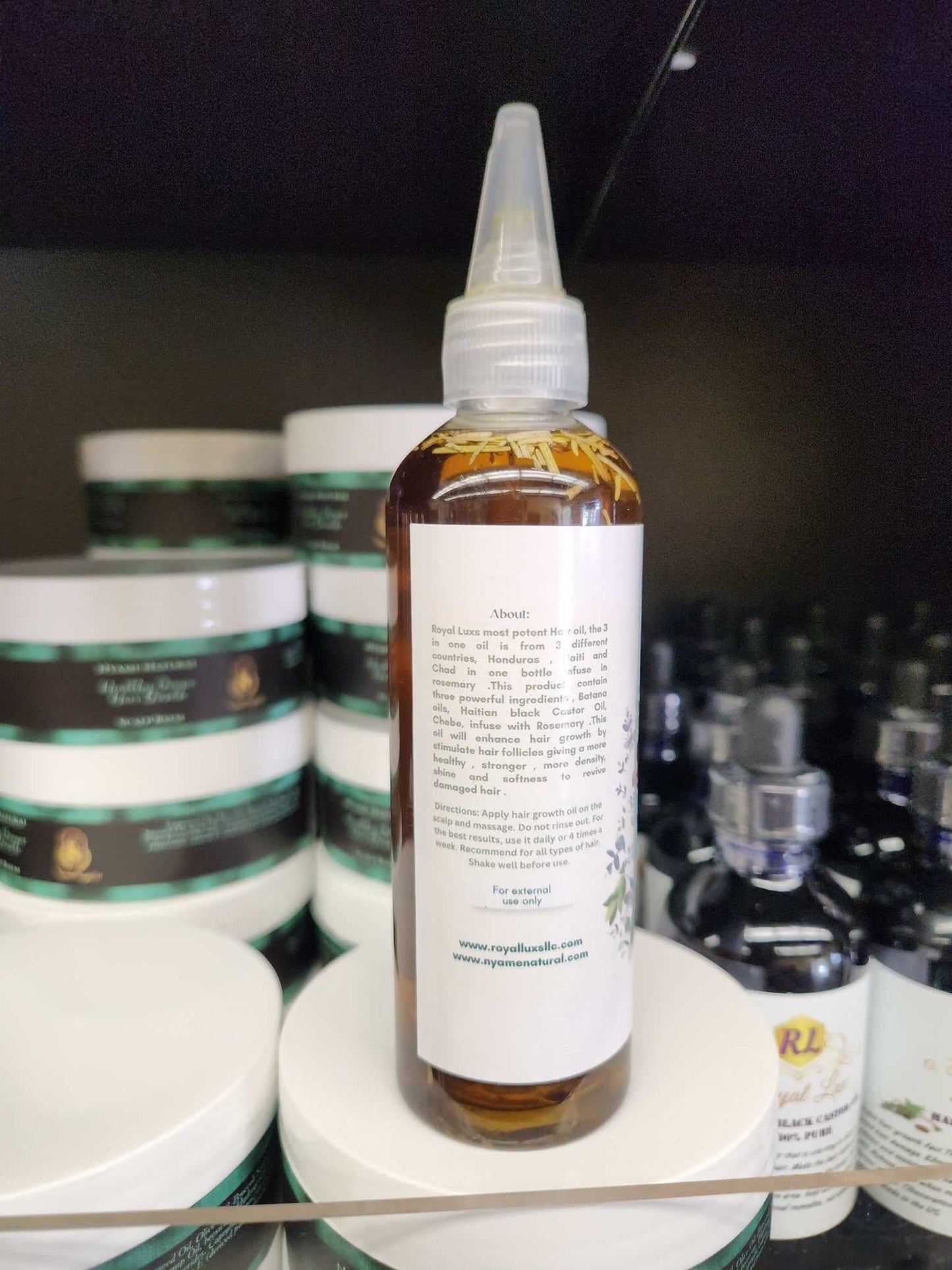 3 in 1 Supergrowth Batana Chebe Haitian Black Castor Oil bottle on display with hair care products behind.