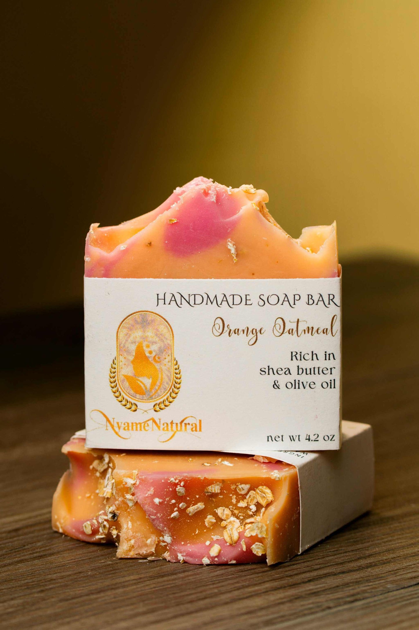 Handmade Orange Oatmeal soap bar rich in shea butter and olive oil on a wooden surface.