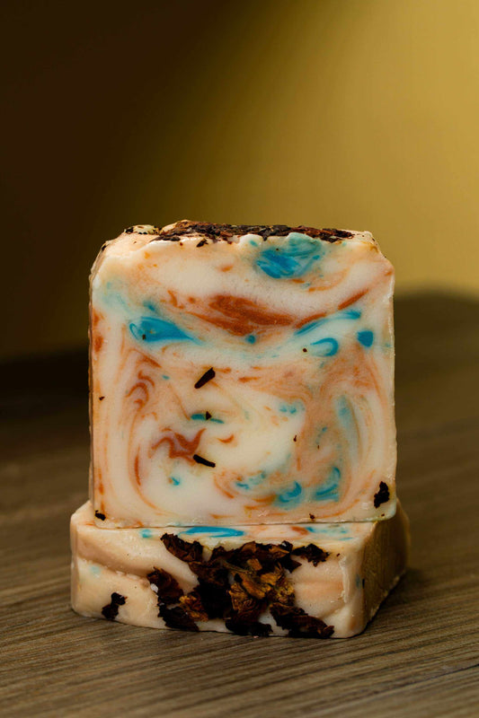 Handmade Milk Rose Petals Bar Soap with swirled blue and brown design on a wooden surface.