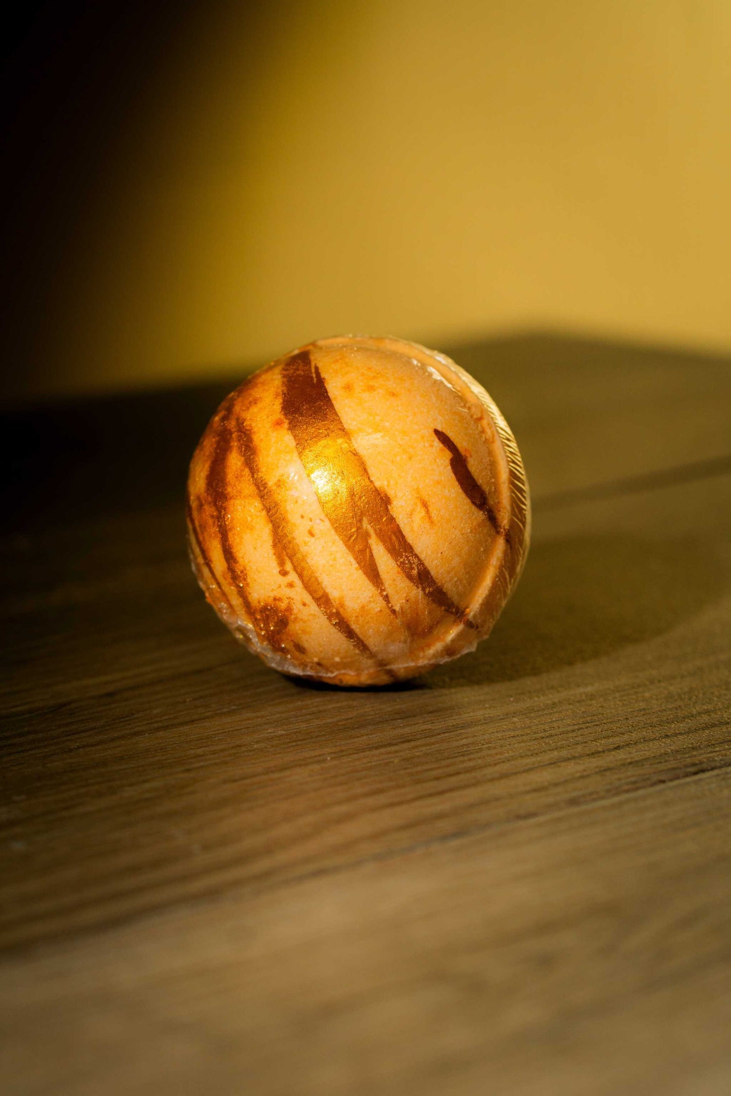 Luxurious Body Bath Bomb with swirls of vibrant colors on a wooden surface.