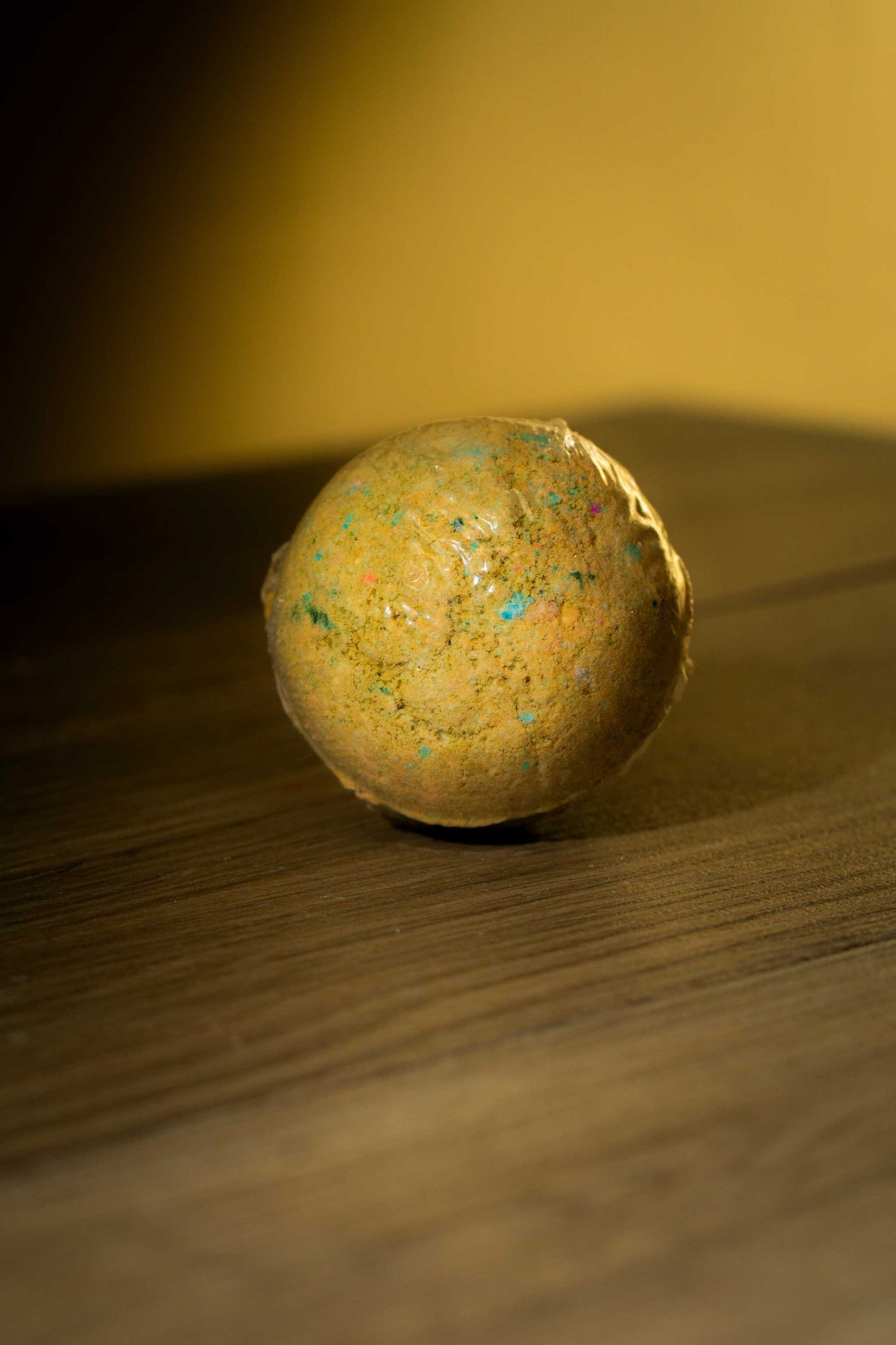 Handcrafted luxurious body bath bomb on a wooden surface, featuring vibrant colors and a soothing design.