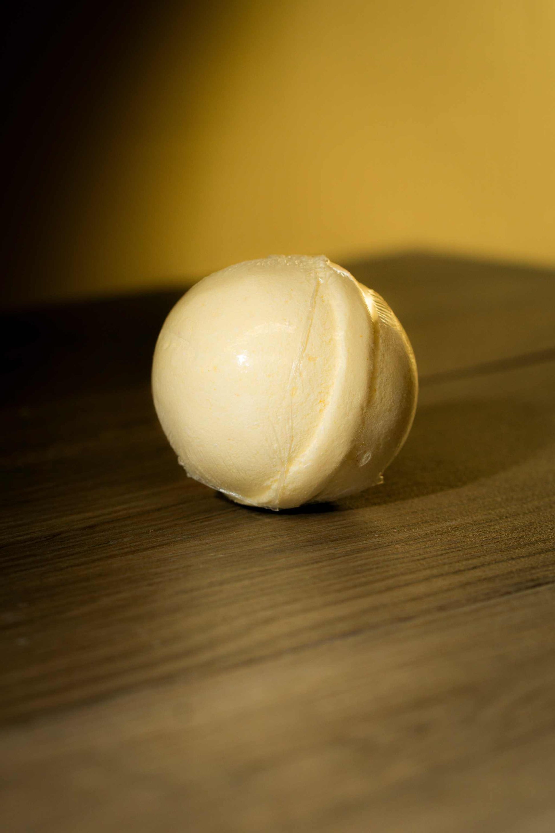 Handcrafted luxurious body bath bomb on a wooden surface, designed for a soothing bathing experience.