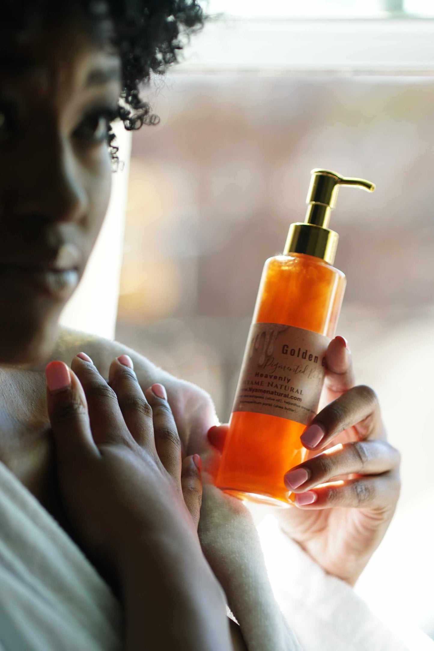 Woman holding a bottle of Copper Pigmented Pheromone Body Oil, highlighting its luxurious golden hue and elegant packaging.