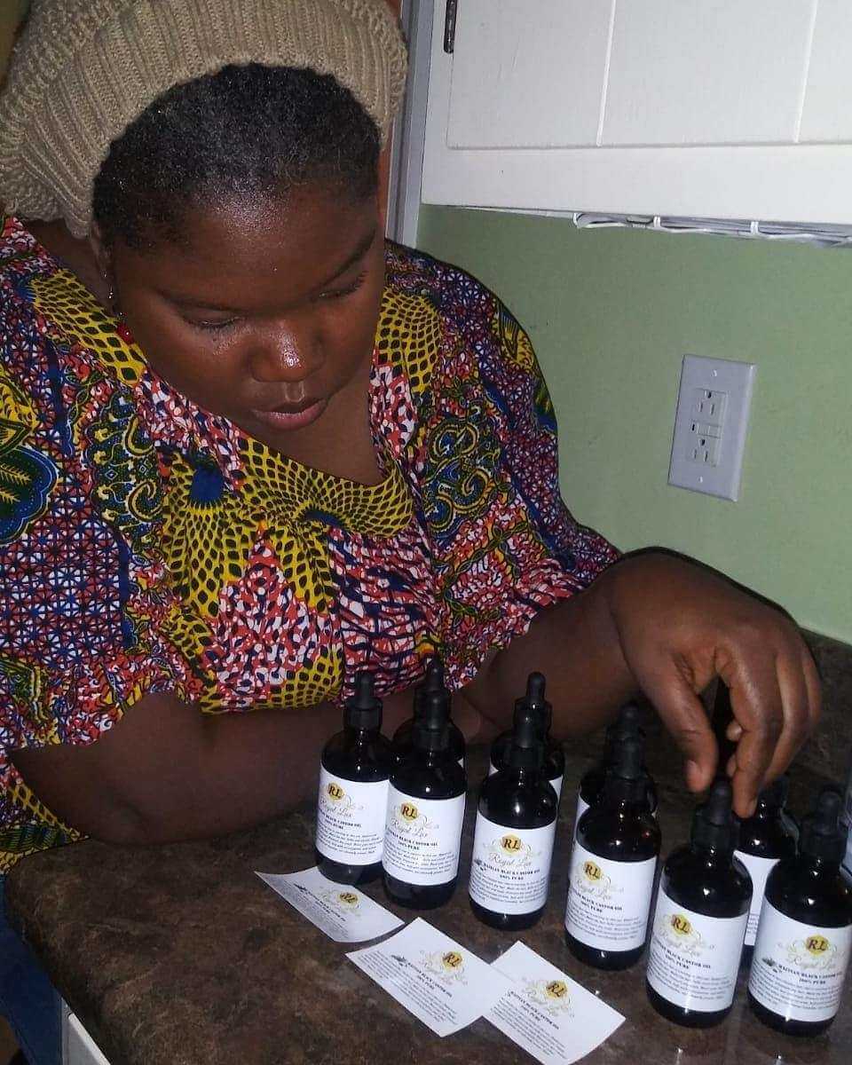 A woman examining bottles of Haitian Black Castor Oil on a table, showcasing her interest in natural hair care.