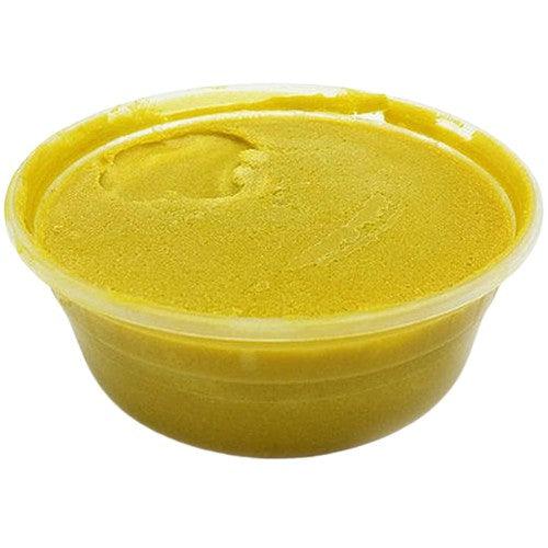 Creamy raw African shea butter in a plastic container, ideal for moisturizing and skin treatment.