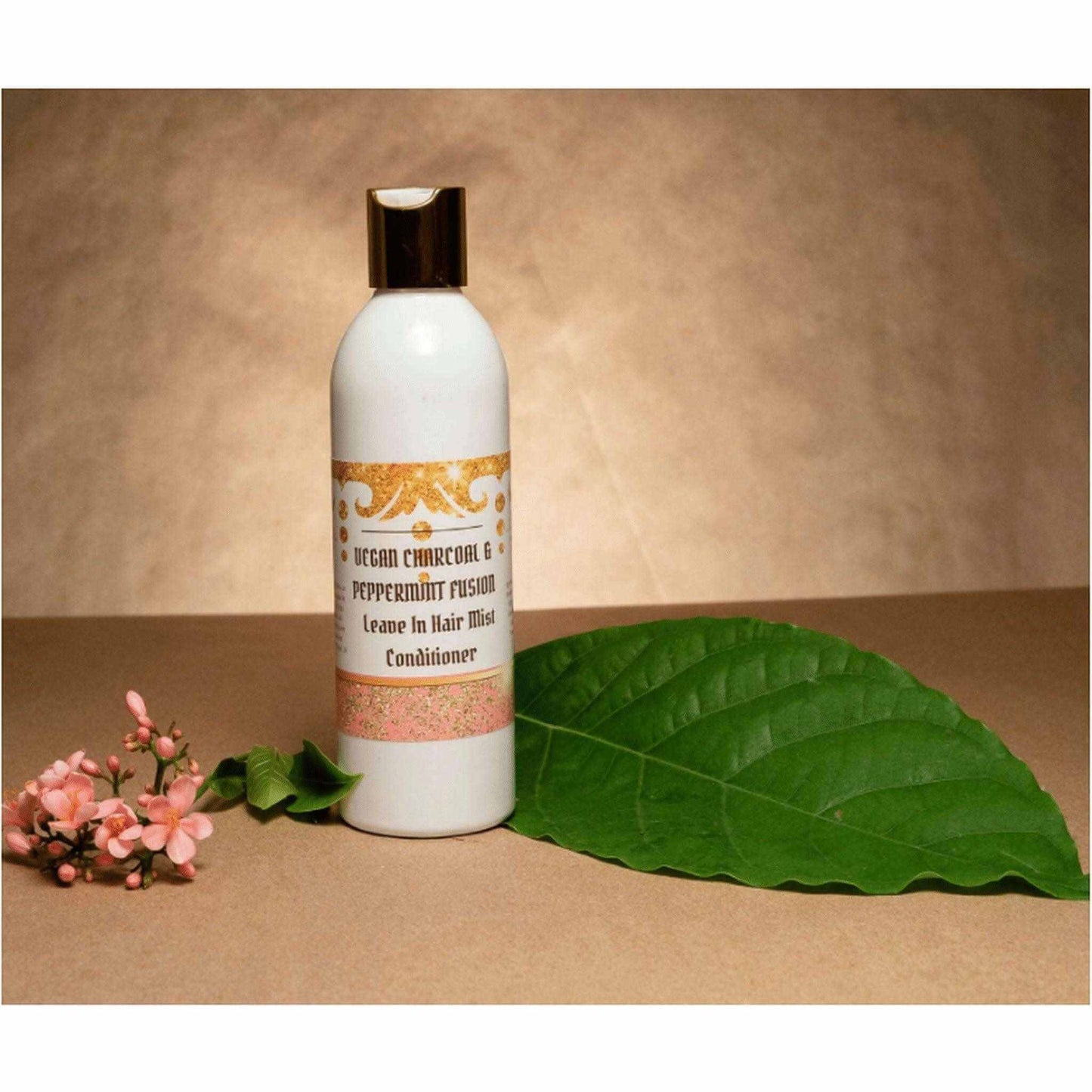 Vegan Charcoal Peppermint Fusion Leave-in Conditioner bottle with floral accents on a neutral background.