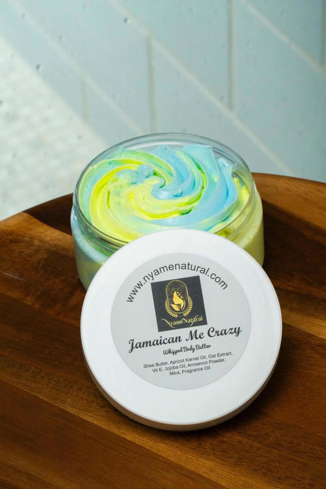 Jamaican Me Crazy Body Butter jar with colorful whipped texture on wooden surface.