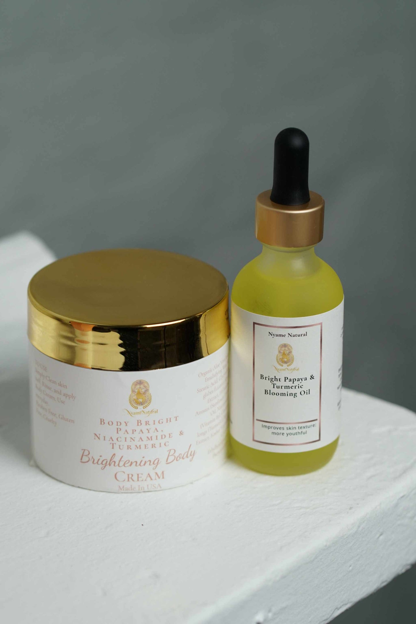 Bright Papaya and Turmeric face oil and cream duo for radiant skin, featuring a gold-topped body cream and vibrant oil.